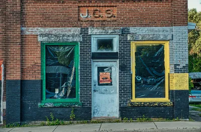 Old brick building with painted frames and closed door in Millville, MN.